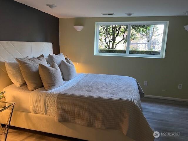 bedroom with visible vents, multiple windows, baseboards, and wood finished floors