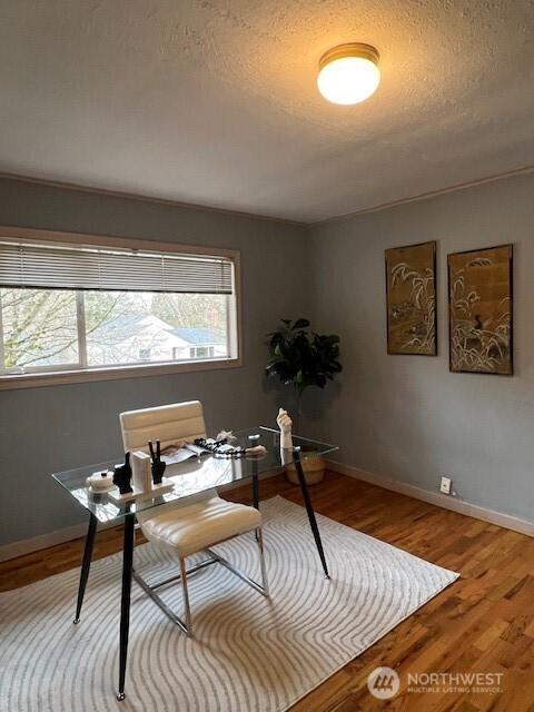 office area featuring a textured ceiling, baseboards, and wood finished floors