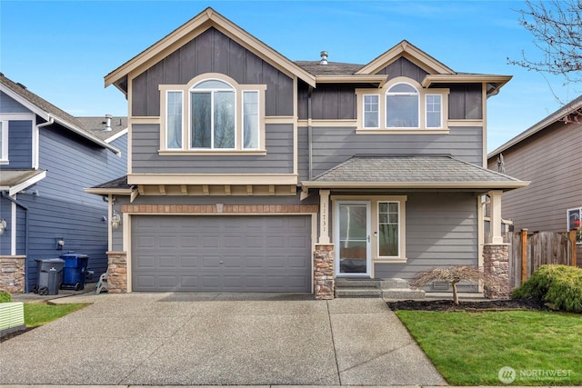 view of front of house with a garage, stone siding, concrete driveway, and fence