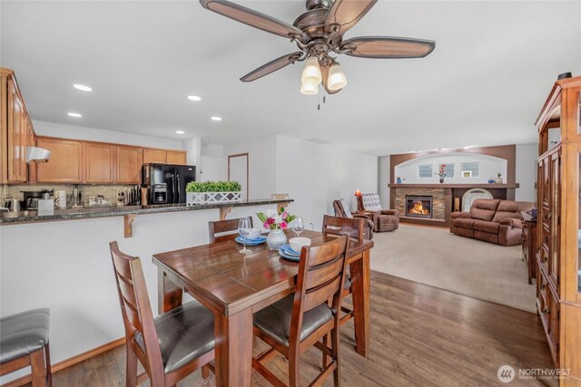 dining area featuring recessed lighting, a fireplace, a ceiling fan, and wood finished floors