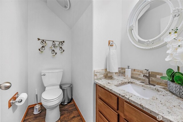 bathroom with baseboards, toilet, wood finished floors, and vanity