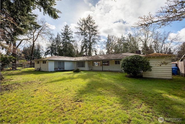 rear view of house featuring a yard and fence