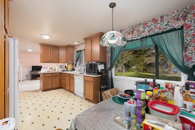 kitchen with pendant lighting, brown cabinetry, black microwave, white dishwasher, and light floors