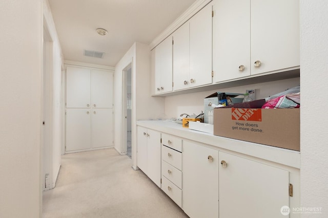 kitchen with visible vents, white cabinetry, light carpet, and light countertops