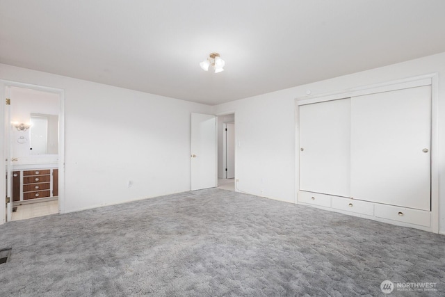 unfurnished bedroom featuring a closet, connected bathroom, and carpet