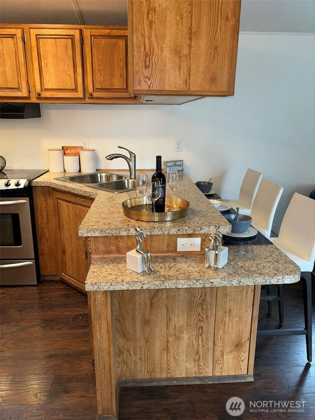 kitchen with a sink, dark wood-type flooring, brown cabinetry, and electric stove