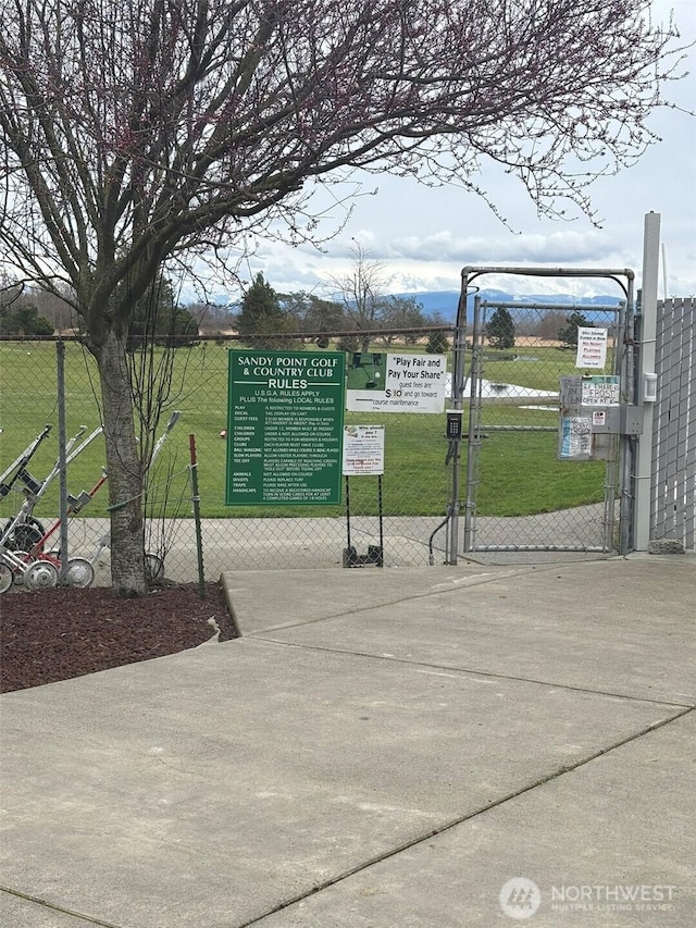 view of property's community with fence, a yard, and a gate