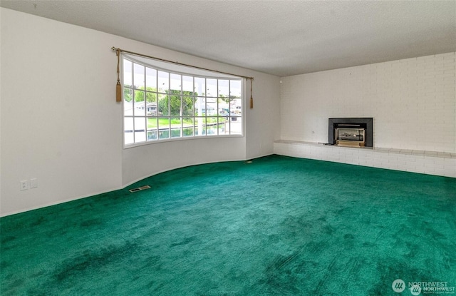 unfurnished living room featuring carpet floors, visible vents, a fireplace, and a textured ceiling