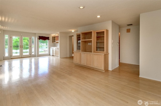 unfurnished living room featuring light wood finished floors, recessed lighting, visible vents, and french doors