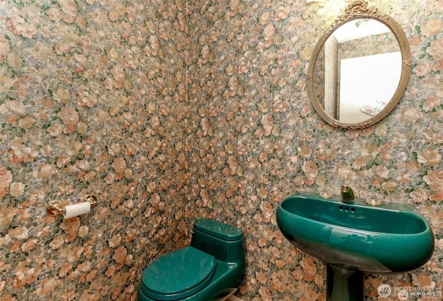 bathroom with toilet and wallpapered walls