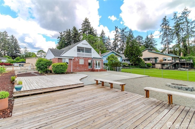 wooden deck with an outdoor fire pit, a lawn, and fence