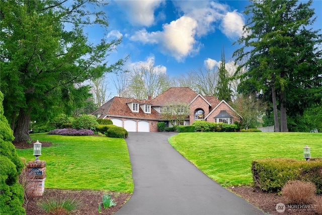 view of front of home with brick siding, aphalt driveway, an attached garage, and a front yard