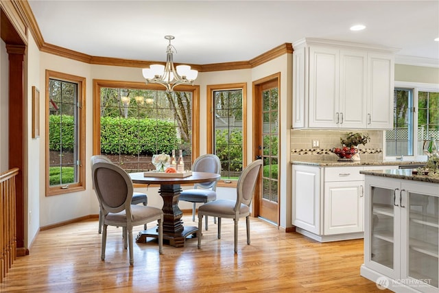 dining area featuring a notable chandelier, ornamental molding, wine cooler, light wood finished floors, and baseboards