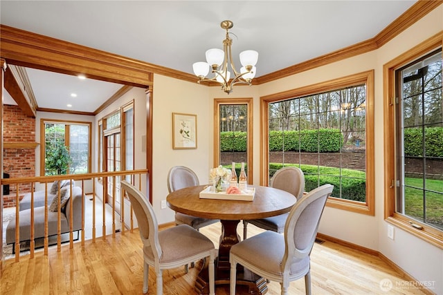 dining room with baseboards, a chandelier, ornamental molding, and light wood finished floors