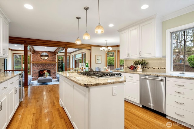 kitchen with a healthy amount of sunlight, appliances with stainless steel finishes, a center island, and a brick fireplace