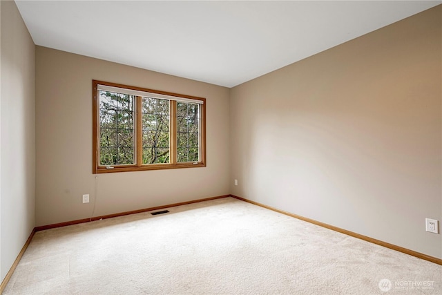 spare room with light colored carpet, visible vents, and baseboards