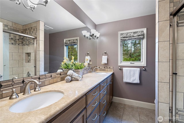 bathroom featuring a sink, a chandelier, baseboards, and a stall shower