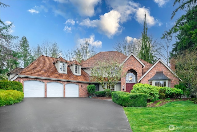 view of front of property featuring brick siding, driveway, a front yard, and a garage