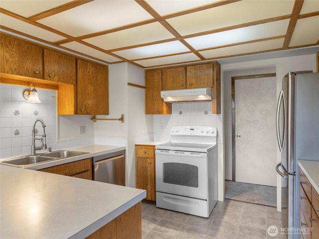 kitchen featuring under cabinet range hood, brown cabinets, appliances with stainless steel finishes, and a sink