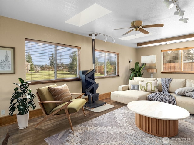 living area featuring a skylight, a textured ceiling, ceiling fan, and wood finished floors