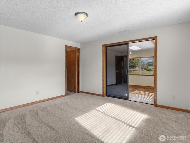 spare room with carpet flooring, a textured ceiling, and baseboards