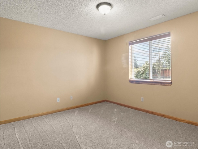 carpeted empty room featuring baseboards and a textured ceiling