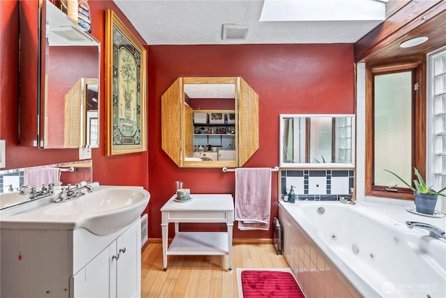 bathroom featuring visible vents, a jetted tub, wood finished floors, and vanity