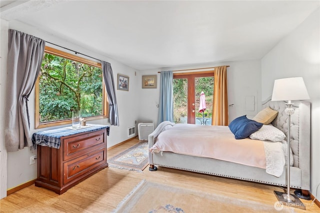 bedroom with access to exterior, light wood-style flooring, and baseboards