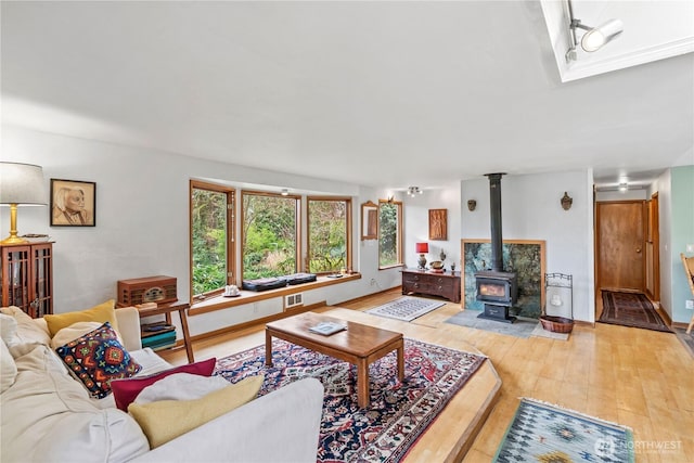 living room featuring a wood stove, hardwood / wood-style flooring, and baseboards