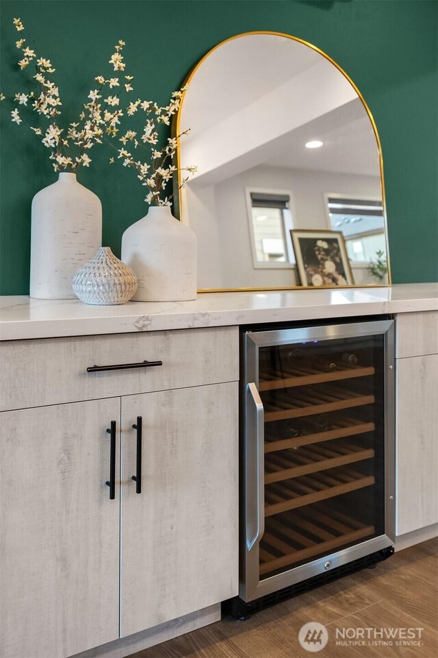 bar featuring beverage cooler, a dry bar, and dark wood finished floors