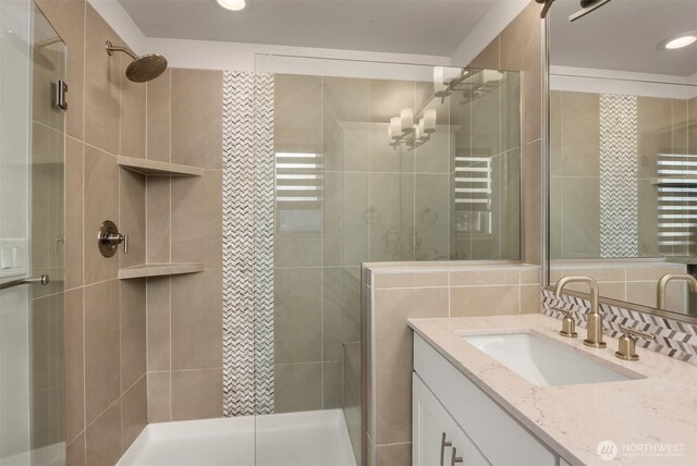 bathroom featuring a shower stall, tasteful backsplash, tile walls, and vanity