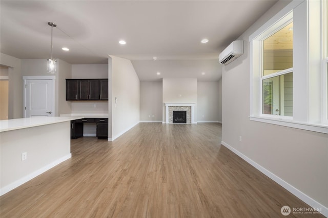 776 Parkland Loop, Sedro Woolley, WA 98284 - unfurnished living room with a wall mounted AC, light wood-type flooring, baseboards, a stone fireplace, and recessed lighting