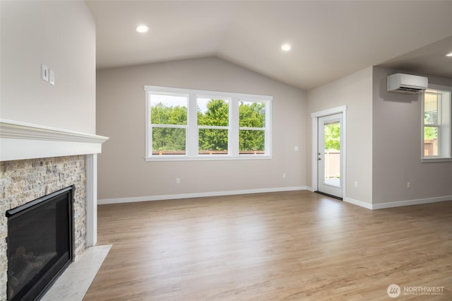 776 Parkland Loop, Sedro Woolley, WA 98284 - unfurnished living room with a wall mounted AC, plenty of natural light, a stone fireplace, vaulted ceiling, and light wood-type flooring