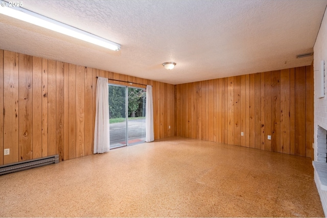 unfurnished room featuring wooden walls, a fireplace, baseboard heating, and a textured ceiling