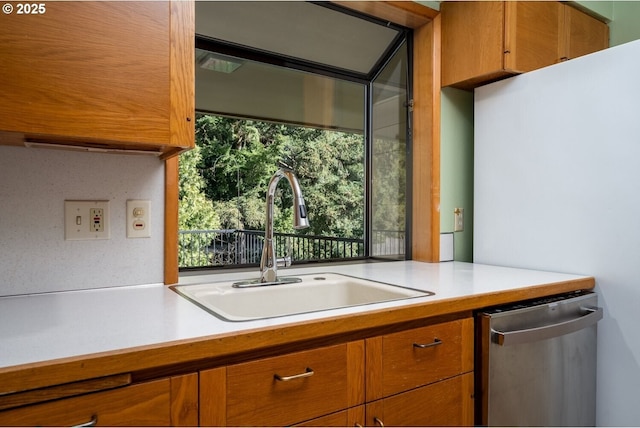 kitchen featuring a wealth of natural light, a sink, brown cabinets, and stainless steel dishwasher