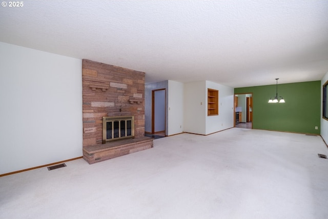 unfurnished living room featuring a notable chandelier, visible vents, a stone fireplace, and carpet