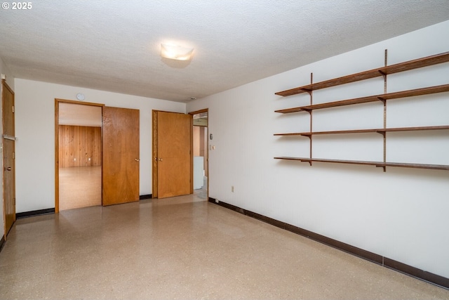 unfurnished bedroom with two closets, speckled floor, baseboards, and a textured ceiling