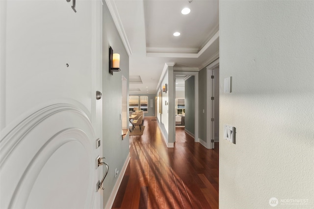 hall with recessed lighting, a tray ceiling, dark wood-type flooring, and baseboards