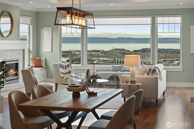 dining room with a wealth of natural light, wood finished floors, crown molding, a premium fireplace, and baseboards