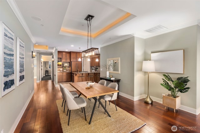 dining area featuring visible vents, a raised ceiling, dark wood-type flooring, and crown molding