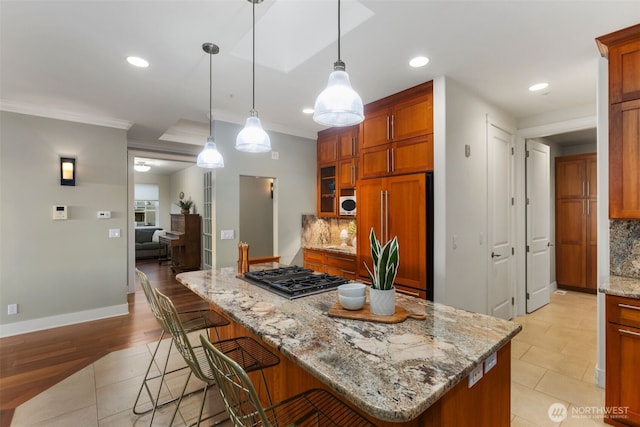 kitchen with brown cabinetry, stainless steel gas cooktop, backsplash, and paneled refrigerator