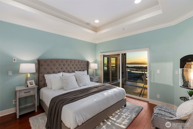 bedroom with access to exterior, a raised ceiling, and wood finished floors