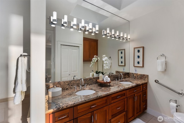 bathroom with a sink, toilet, and double vanity