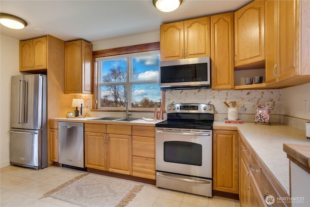 kitchen with tasteful backsplash, light countertops, light tile patterned floors, stainless steel appliances, and a sink