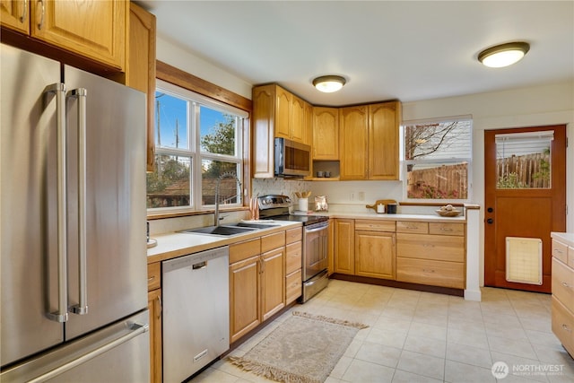 kitchen featuring a sink, backsplash, appliances with stainless steel finishes, and light countertops