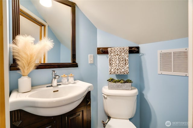 bathroom with vanity, lofted ceiling, toilet, and visible vents