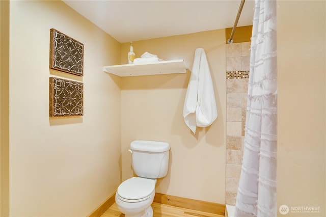 full bathroom with baseboards, tiled shower, toilet, and wood finished floors