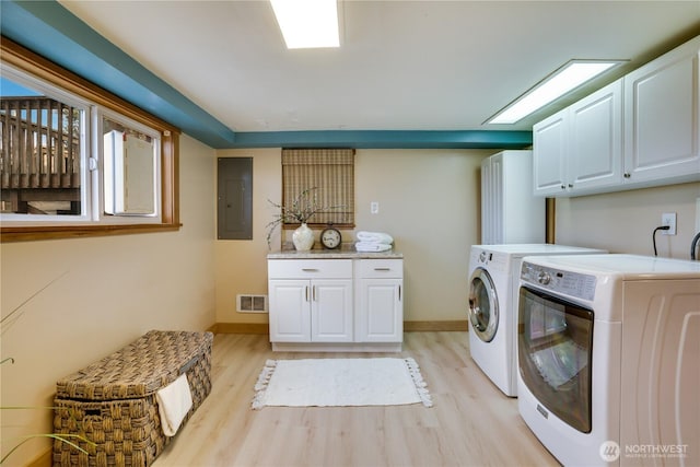 clothes washing area with visible vents, light wood-style flooring, washer and dryer, electric panel, and cabinet space