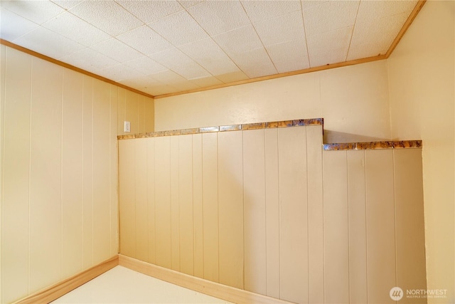 bathroom featuring crown molding and wooden walls