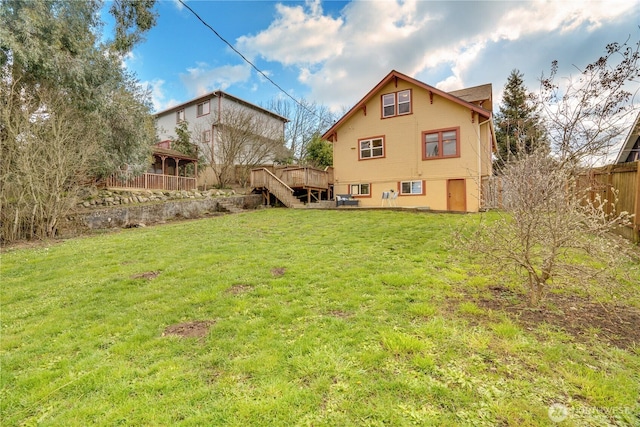 rear view of house featuring a yard, a wooden deck, stairs, and fence